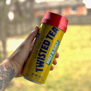 May include: A yellow can of Twisted Tea Hard Iced Tea with a red lid. The can has the text "Hard Iced Tea" and "Twisted Tea" in blue lettering. The can also has the text "Half & Half" in blue lettering. The can has a 5% alcohol content.