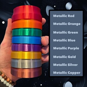 May include: A stack of eight round, metallic colored plastic discs. The colors are red, orange, green, blue, purple, gold, silver, and copper. The discs are stacked in order from top to bottom, with the red disc on top and the copper disc on the bottom.
