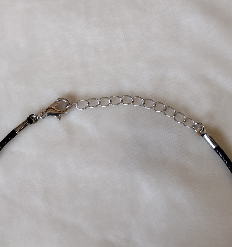 May include: A black cord necklace with a silver clasp and extender chain.