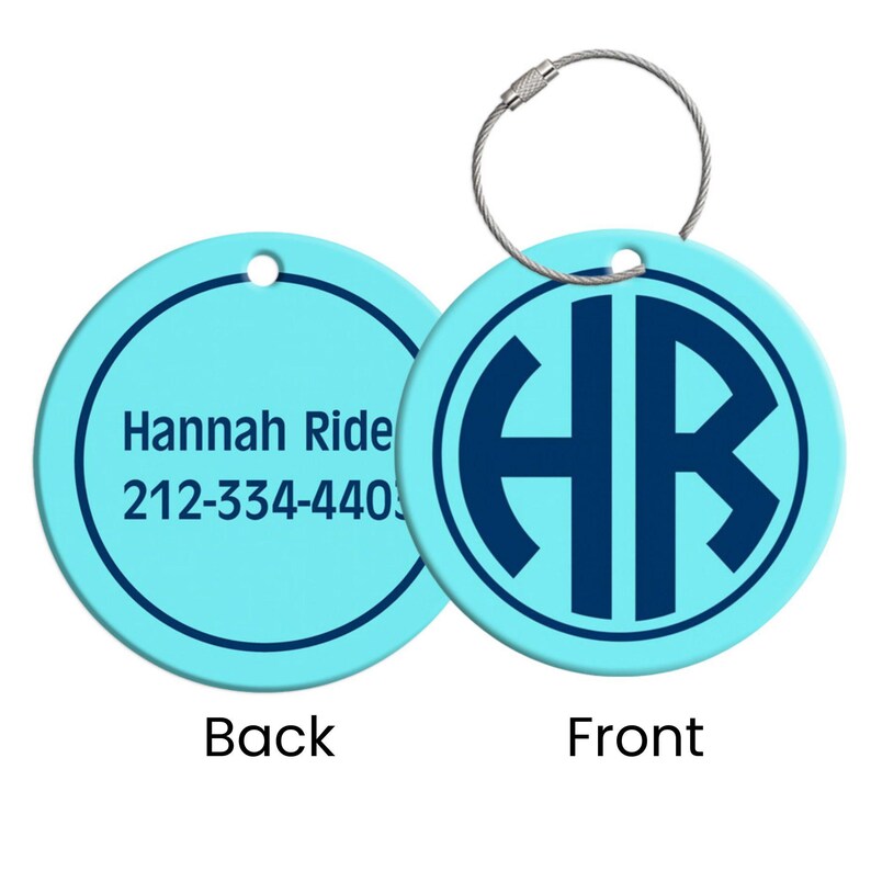 May include: A light blue luggage tag with a silver-colored wire loop. The front features a dark blue monogram within a circle. The back has the name "Hannah Ride" and a phone number.
