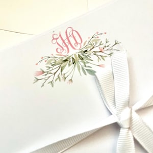 May include: A white envelope with a pink floral design and the monogram "HO" in pink. The envelope is tied with a white ribbon.
