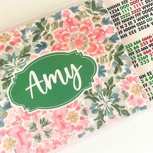 May include: A floral patterned organizer with a green label that says "Amy" in white script. The design features pink, blue, and green watercolor flowers. Additional text is visible on the right side of the organizer.