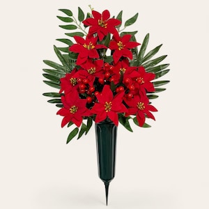 Puede incluir: Un vibrante arreglo de flores de pascua rojas y bayas rojas, acentuado por hojas verdes, exhibido en un jarrón verde oscuro. El arreglo floral está diseñado para uso en exteriores, con una base puntiaguda para facilitar la colocación.