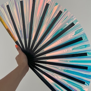 May include: A black and iridescent fan with a gold handle. The fan is made of multiple layers of iridescent material, each with a black stripe.