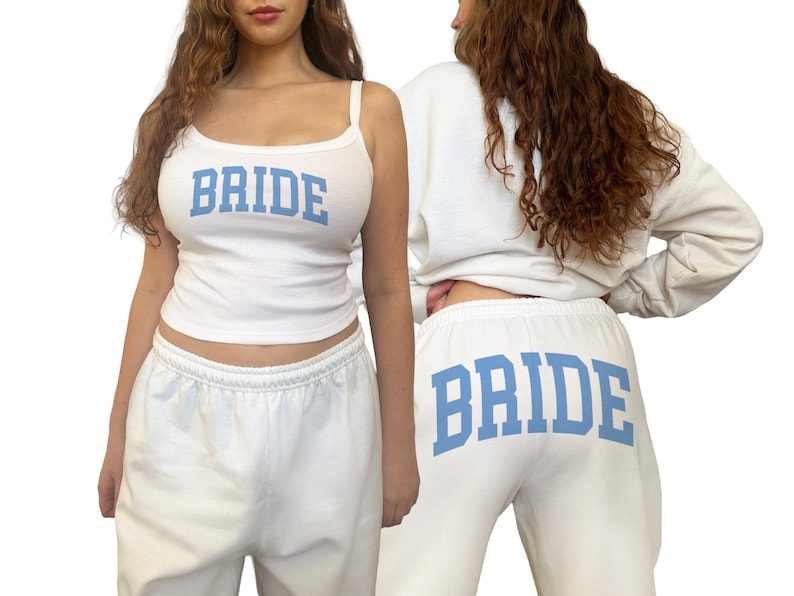 May include: White bridal loungewear set featuring a tank top and sweatpants. The tank top has thin straps and the word "BRIDE" in light blue block letters. The sweatpants also display "BRIDE" in the same font and color.