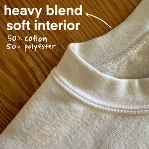 Pu&ograve; includere: Primo piano del colletto di una felpa color crema. Il testo indica che si tratta di un misto pesante con interno morbido, realizzato al 50% in cotone e al 50% in poliestere. Il colletto &egrave; cucito con cura.