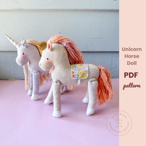 May include: Two plush unicorn horse dolls with pink and peach manes and tails. One has a white horn and the other has a gold crown. The dolls have floral saddle blankets. The text "Unicorn Horse Doll PDF pattern" is visible.