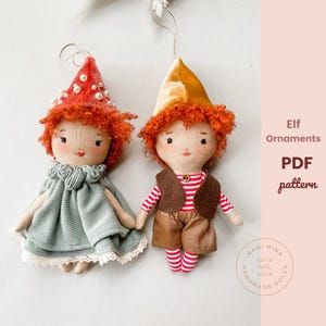 May include: Two handmade elf ornaments. One elf wears a red and white mushroom cap with pearls, a blue dress, and a white lace collar. The other elf wears a brown vest, red and white striped shirt, brown shorts, and red and white striped socks. The text "Elf Ornaments PDF pattern" is visible.