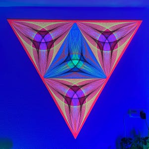 May include: A triangular wall art piece with a geometric design. The artwork uses pink, yellow, blue, and green threads to create a layered pattern. The artwork is mounted on a blue wall, creating a striking contrast. The piece is a modern art statement.