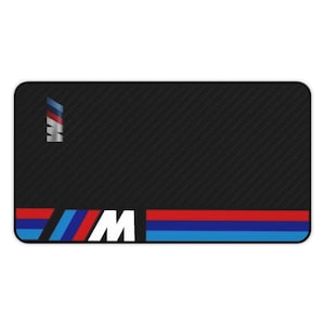 May include: Black mousepad with a carbon fiber pattern and a white "M" logo with blue and red stripes.