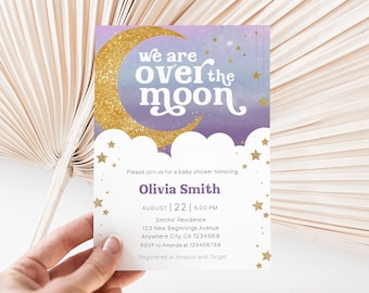 May include: Baby shower invitation with a celestial theme. The design features a gold glitter crescent moon and stars against a purple and blue watercolor background. The text "We are over the moon" is displayed above the invitation details.