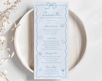May include: A light blue baby shower menu with a bow and heart design at the top. The menu lists starters, mains, dessert, and drinks, including mini croissant sandwiches, pancakes, and strawberry lemonade. The menu is on a wooden plate.