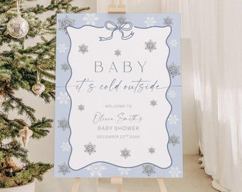 May include: A light blue baby shower sign with a snowflake design and the text "BABY it's cold outside". The sign welcomes guests to Olivia Smith's baby shower on December 22nd, 20XX. The sign is displayed on a wooden easel.