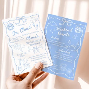 Peut inclure: Deux cartons d'invitation bleu clair pour un enterrement de vie de jeune fille avec du texte et des illustrations blanches. L'un indique "On Cloud 9" et détaille l'événement. L'autre liste les événements du week-end.