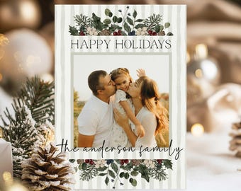 May include: A holiday card with a family photo, the text "HAPPY HOLIDAYS" and "the anderson family". The card has a striped background and floral accents in green, white, and burgundy. The family photo shows a man, woman, and child.