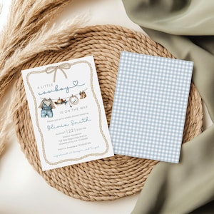 May include: Baby shower invitation with a cowboy theme. The invitation features a watercolor illustration of cowboy attire, including overalls and a hat, with the text "A Little Cowboy Is On The Way." The back of the invitation has a blue and white gingham pattern.