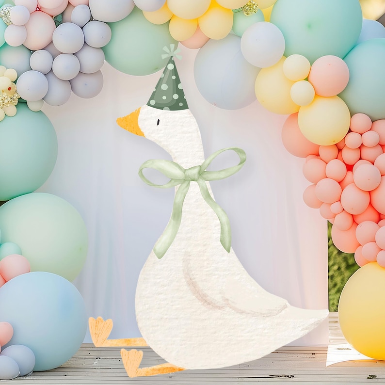 May include: A white goose wearing a green party hat with a green bow. The goose is surrounded by pastel colored balloons.