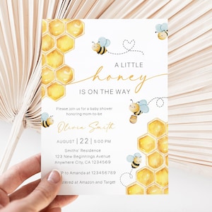 Può includere: Un invito per un baby shower con un design ad acquerello. L'invito presenta un motivo a nido d'ape, api e il testo "A Little Honey Is On The Way". L'invito include la data, l'ora e il luogo.