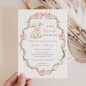 Puede incluir: Invitación a un baby shower con una ilustración de un cordero y el texto "a little lamb is on the way". La invitación incluye los detalles del evento: fecha, hora y lugar. El diseño incorpora elementos rosas y florales.