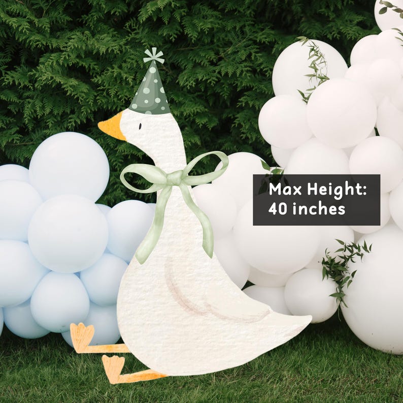 May include: A white goose party decoration with a green hat and a green bow. The goose is sitting on a bed of white and blue balloons. The text "Max Height: 40 inches" is visible in the image.