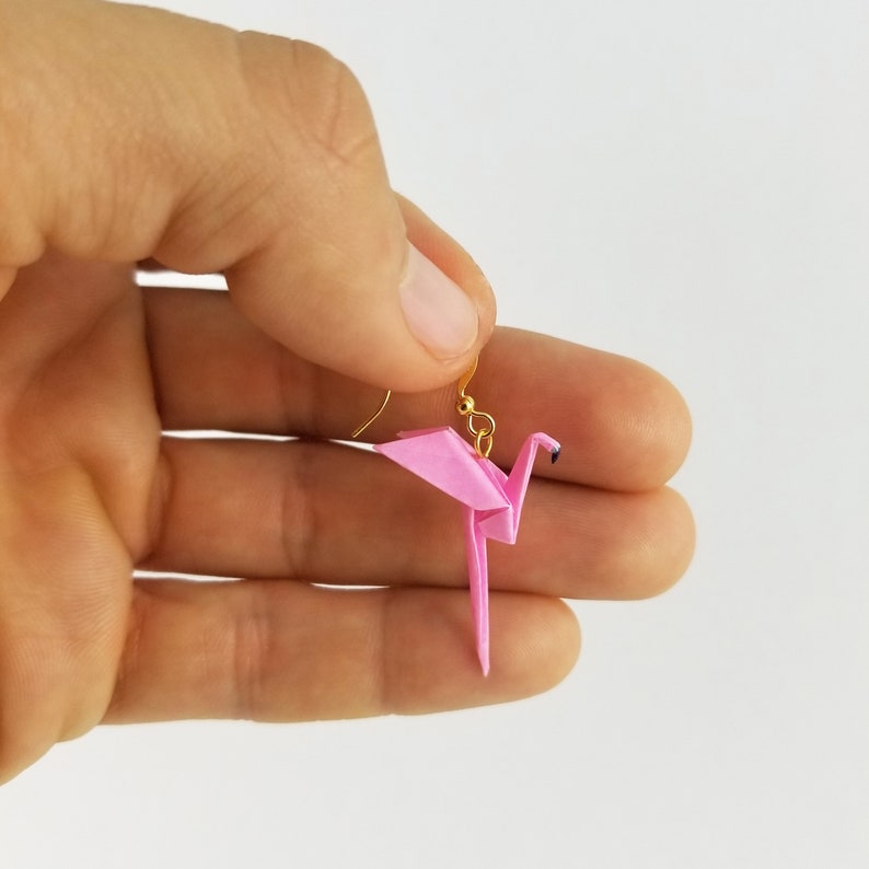 May include: Pink origami crane earrings with gold hooks. The crane is a traditional Japanese symbol of peace and good luck.