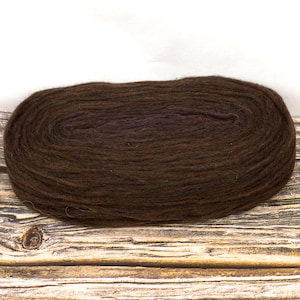 Puede incluir: Una madeja de hilo marrón oscuro, ideal para proyectos de tejido o ganchillo. El hilo tiene un aspecto suave y texturizado, presentado sobre una superficie de madera rústica.