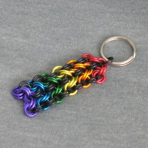 May include: A rainbow colored chain keychain with a silver key ring. The chain is made of small metal rings in a variety of colors, including red, orange, yellow, green, blue, and purple.
