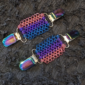 May include: Two iridescent metal chainmail garment clips with a purple, blue, and pink chainmail design.