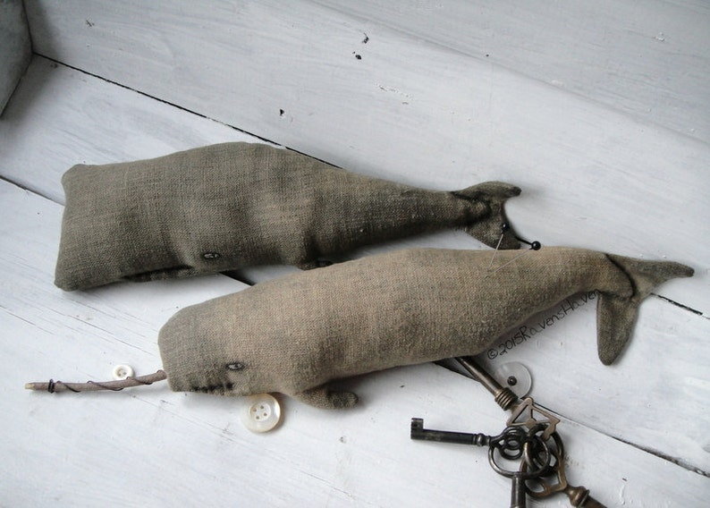 May include: Two gray fabric whale plushies with button eyes. The whales are lying on a white wooden surface with antique keys and buttons scattered around them.  &copy;2015 RavenHive