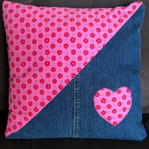 Peut inclure: Coussin carré décoratif avec un design divisé en diagonale. Une moitié présente un motif floral rose, l'autre est en jean. Un cœur floral rose est cousu sur le côté en jean. Conçu pour la décoration intérieure.