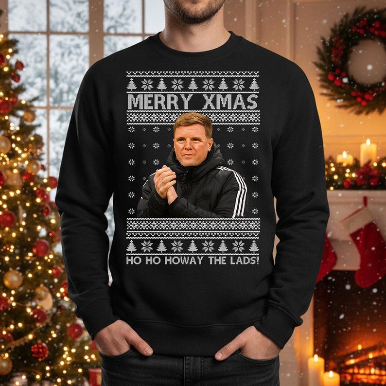 May include: Black sweatshirt with a festive design. The text "MERRY XMAS" is at the top, with a portrait of a man in the center. Below the portrait is the text "HO HO HOWAY THE LADS!" The design includes snowflakes and Christmas trees.