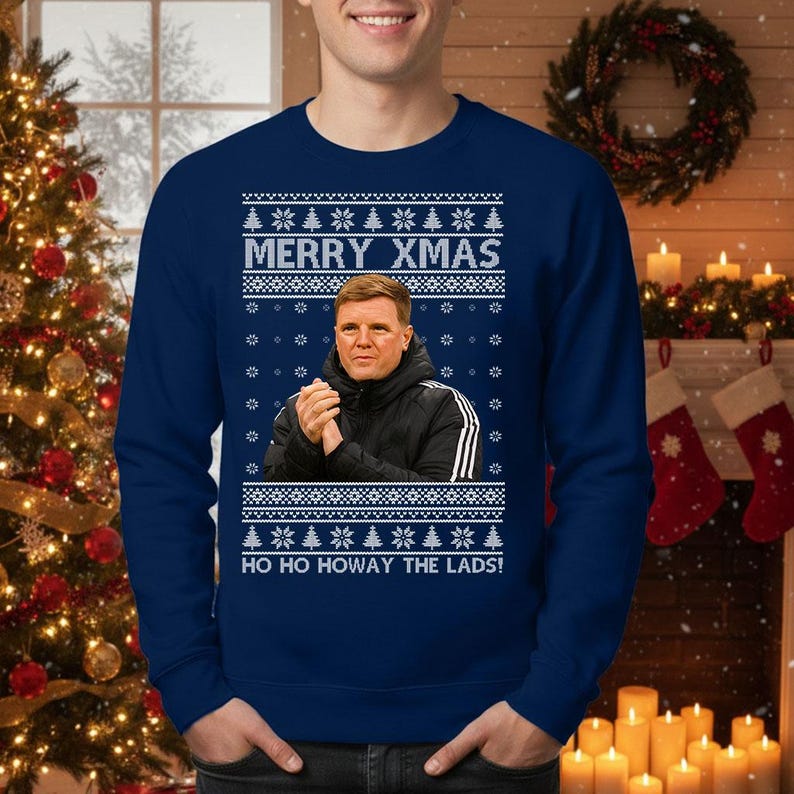 May include: Navy blue Christmas sweater with a festive design. The sweater features the text "MERRY XMAS" and "HO HO HOWAY THE LADS!" along with a portrait of a man. The design includes snowflakes and Christmas trees.