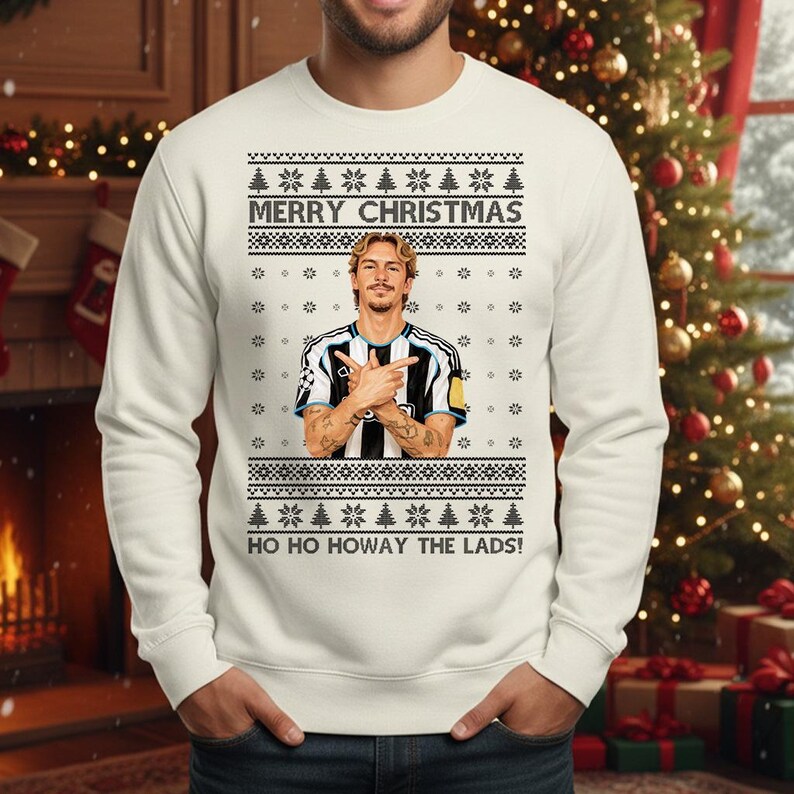 Puede incluir: Jersey navide&ntilde;o color crema con un dise&ntilde;o festivo. El jersey presenta el texto "MERRY CHRISTMAS" y "HO HO HOWAY THE LADS!". Tambi&eacute;n incluye un gr&aacute;fico de una persona con una camiseta de f&uacute;tbol. El jersey tiene cuello redondo cl&aacute;sico y mangas largas.