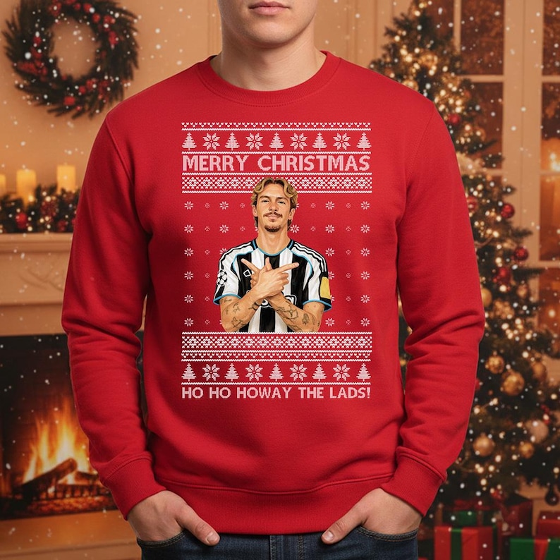 Puede incluir: Jersey navide&ntilde;o rojo con un dise&ntilde;o festivo. El jersey presenta un retrato de un hombre con una camiseta de f&uacute;tbol, con el texto "MERRY CHRISTMAS" y "HO HO HOWAY THE LADS!" en blanco. El dise&ntilde;o incluye copos de nieve y &aacute;rboles de Navidad.