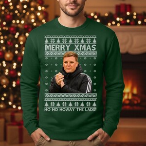 May include: Green Christmas sweater with the text "MERRY XMAS" and "HO HO HOWAY THE LADS!". The sweater features a portrait of a man in a black jacket. White snowflake and Christmas tree patterns are also present.