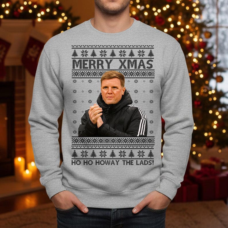 May include: Gray sweatshirt with a festive design. The text "MERRY XMAS" is displayed above a portrait. Below the portrait, the text "HO HO HOWAY THE LADS!" is printed. The design includes snowflakes and Christmas trees.