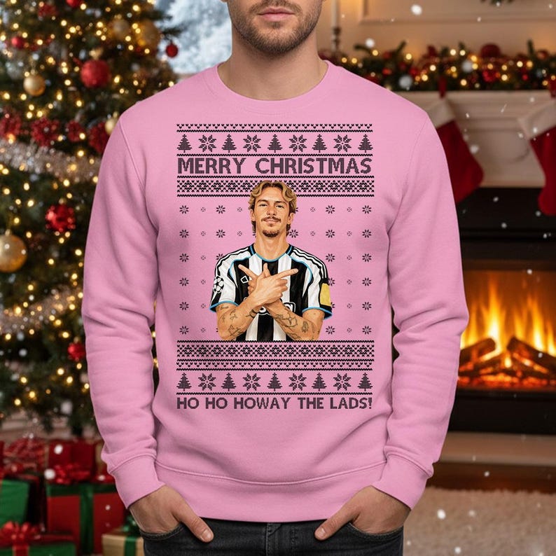 Puede incluir: Su&eacute;ter navide&ntilde;o rosa con el texto "MERRY CHRISTMAS" y "HO HO HOWAY THE LADS!". El su&eacute;ter presenta un gr&aacute;fico de una persona con una camiseta a rayas blancas y negras. El su&eacute;ter tiene un dise&ntilde;o festivo con copos de nieve y &aacute;rboles de Navidad.