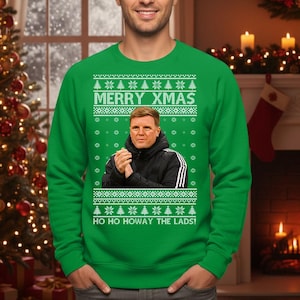 May include: Green Christmas sweater with the text "MERRY XMAS" and "HO HO HOWAY THE LADS!". The sweater features a portrait of a man in a black jacket. The sweater has a festive pattern of snowflakes and Christmas trees.