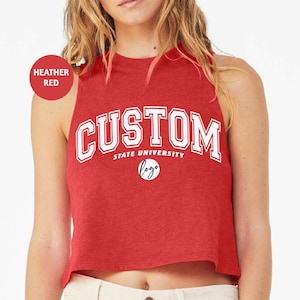 May include: Heather red sleeveless crop top with the text "CUSTOM STATE UNIVERSITY" in white with a circle containing the word "logo" in black.
