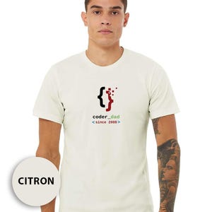 May include: A citron-colored t-shirt with a graphic design featuring a black and red bracket symbol and the text "coder_dad <since 2008>". The shirt is short-sleeved and made of a soft material.