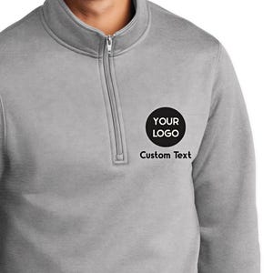 a man wearing a grey sweatshirt with a black heart on it