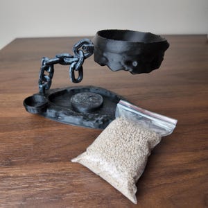 May include: A black, 3D-printed incense holder with a chain design supporting a bowl. A small dish and a bag of incense granules are also present. The holder is on a wooden surface.