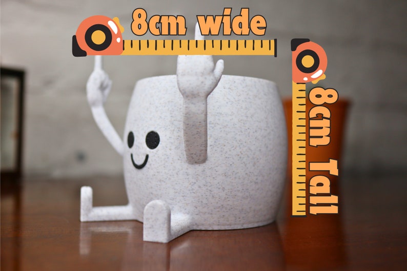 May include: A white ceramic planter with a smiling face and arms and legs. The planter is 8 cm wide and 8 cm tall.