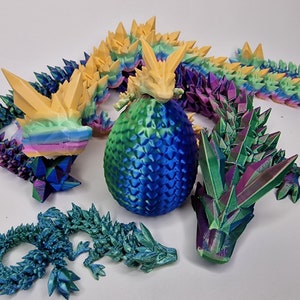 May include: A set of 3D printed iridescent dragon figurines. The dragons are in various poses, including a curled up dragon, a dragon with its wings spread, and a dragon with its head raised. The dragons are all made of a shiny, iridescent material that changes color in the light.