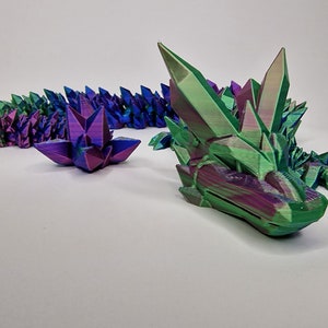 May include: A 3D printed iridescent dragon sculpture with a green and purple color scheme. The dragon is made up of many small, pointed crystals.