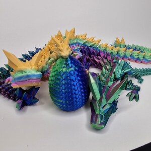 May include: A 3D printed iridescent dragon with a blue egg and a smaller iridescent dragon. The dragon is made of multiple pieces and has a rainbow color scheme.