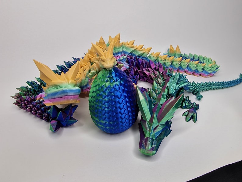 May include: A 3D printed iridescent dragon with a blue egg and a smaller iridescent dragon. The dragon is made of multiple pieces and has a rainbow color scheme.