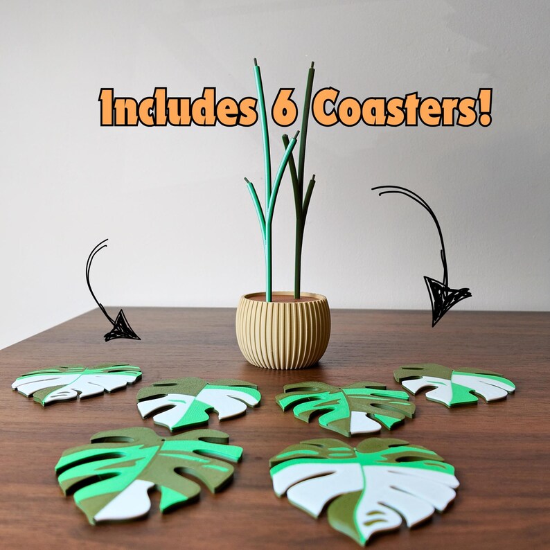 May include: A set of six leaf-shaped coasters in shades of green and white, arranged on a wooden surface. A decorative vase with green stems is in the background. The text "Includes 6 Coasters!" is displayed in orange.