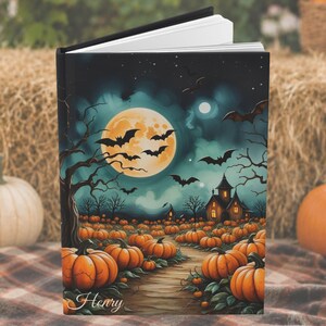 May include: A hardcover book featuring a Halloween-themed illustration of a pumpkin patch under a full moon with bats and a dark house. The cover displays a path winding through orange pumpkins toward the house, with the name Henry written in script.