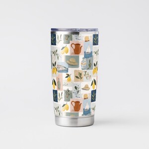 May include: A stainless steel travel tumbler with a colorful, patterned design. The pattern features a collage of lemons, teapots, hats, and sailboats in a grid of squares. The tumbler has a silver base and a dark blue lid.